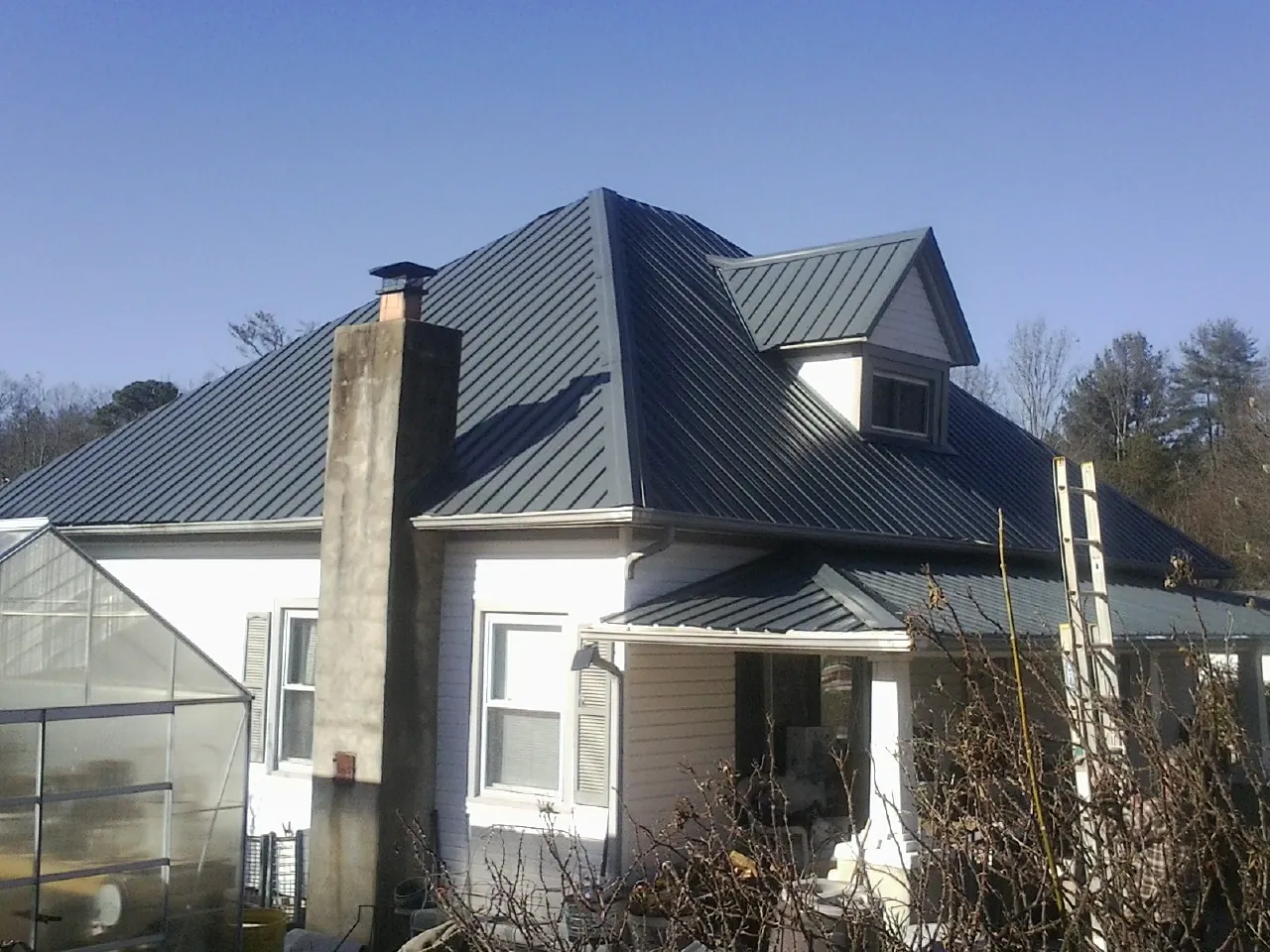 Dark blue standing seam metal roof on a white farmhouse with dormer — Slate & Tile Roof Repair by Roofing Brothers in Somonauk