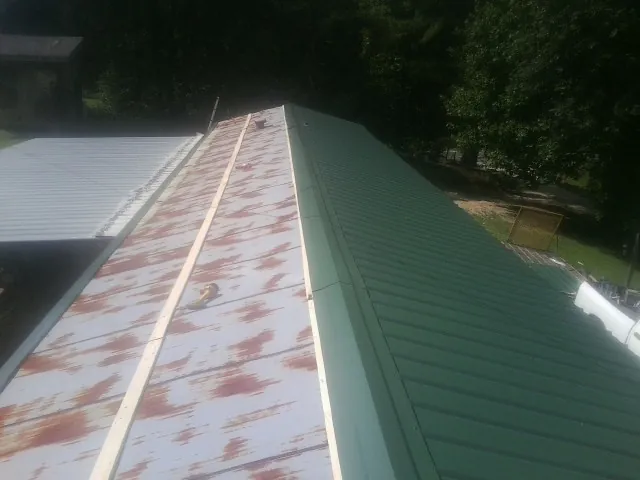 Old rusted panels beside newly installed green metal roofing — Wind Damage Roof Repair by Roofing Brothers in Somonauk