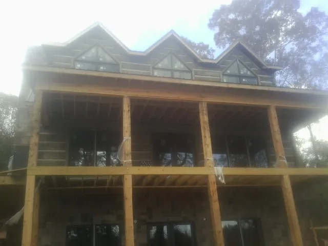 Dormers and porch framing on a large log home under construction — Roof Coating work by our crew in Somonauk