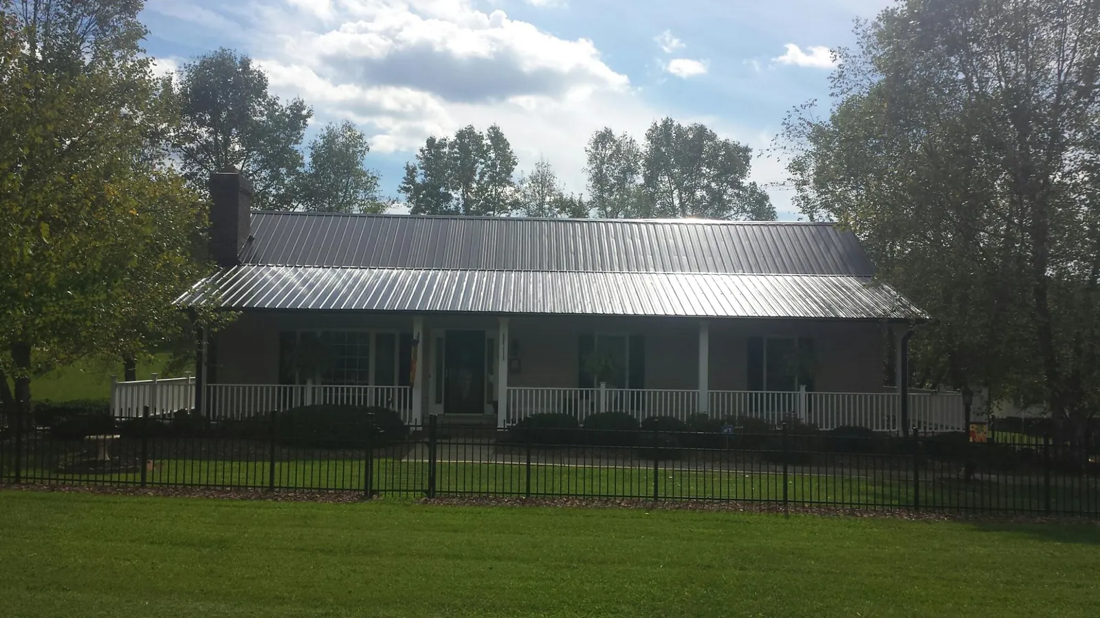Gray metal roof on a brick ranch with a full width front porch — Gutter Guard Installation work by our crew in Somonauk