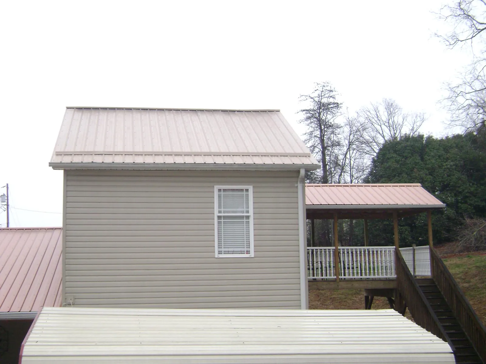 Tan metal roofs on a two story addition and attached porch, from a Roof Replacement job in Somonauk