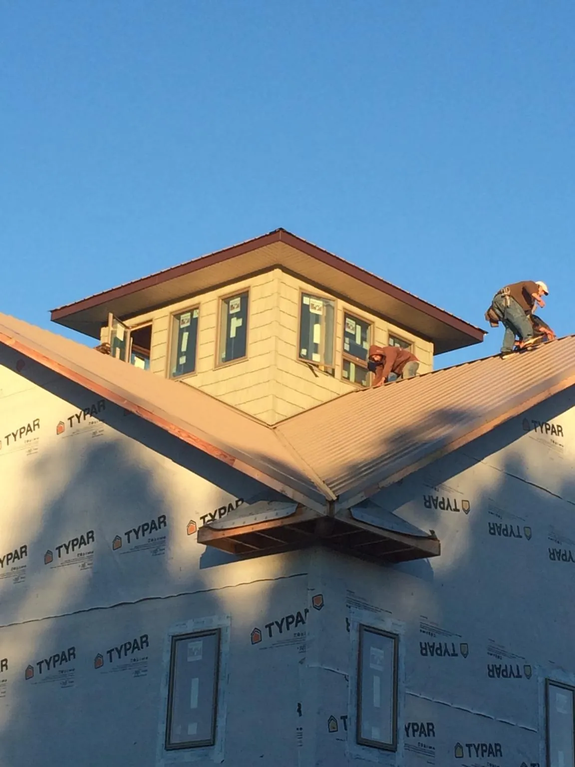 Roofers working around a rooftop cupola on a new metal roof at sunset — Roof Waterproofing in Somonauk by Roofing Brothers
